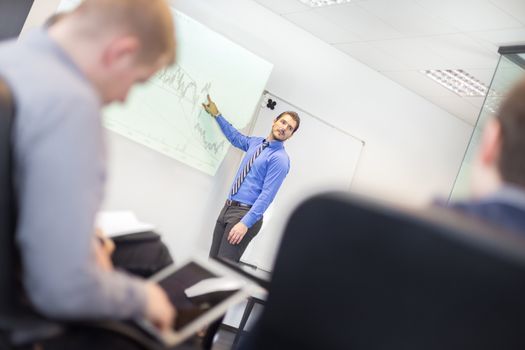 Business man making a presentation at office. Business executive delivering a presentation to his colleagues during meeting or in-house business training, explaining business plans to his employees. 