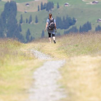 Hiker, young woman with backpack walking on footpath, Switzerland