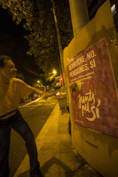 SPAIN, Barcelona: An activist from the pro-independence coalition Junts pel Si (Together for Yes) sticks up posters around Barcelona on the evening of September 16, 2015. Pro-independence groups are rallying their supporters ahead of the Catalonian parliamentary election, taking place on September 27.