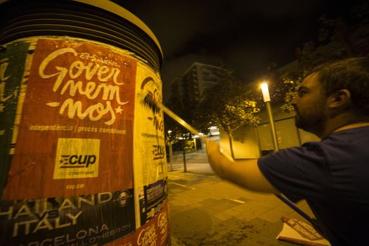 SPAIN, Barcelona: An activist from the pro-independence coalition Junts pel Si (Together for Yes) sticks up posters around Barcelona on the evening of September 16, 2015. Pro-independence groups are rallying their supporters ahead of the Catalonian parliamentary election, taking place on September 27.