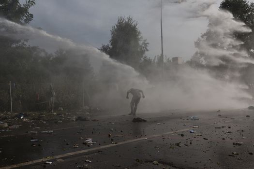 SERBIA, Horgos: A man ducks as Hungarian police fire tear gas and water cannons into the refugees in the Serbian border town of Horgos on September 16, 2015, after Hungary closed its border in an effort to stem the wave of refugees entering the country. ****Restriction: No Russia or Asia sales****