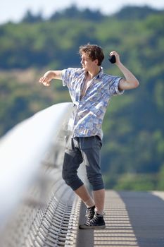 Young Man Standing on the Bridge Throwing Down Something