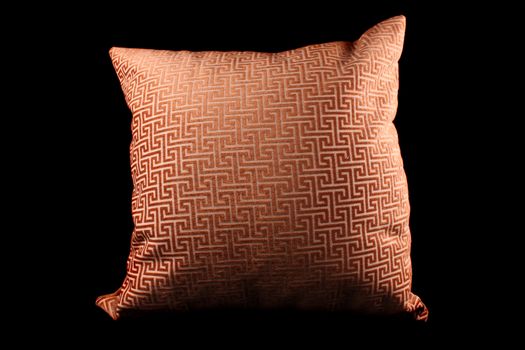 A designer pillow with abstract design, on black studio background.
