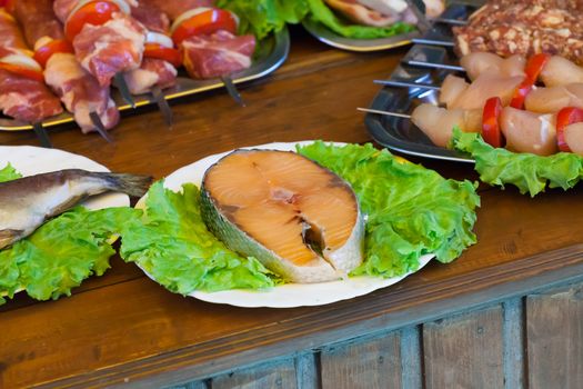 stake of a salmon on a white plate with greens on a wooden table