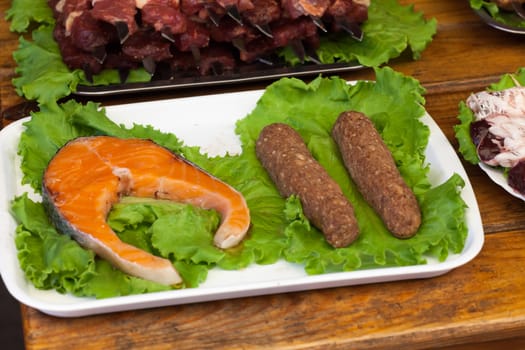 stake of a salmon on a white plate with greens on a wooden table
