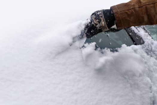 Man scraping snow and ice from car window