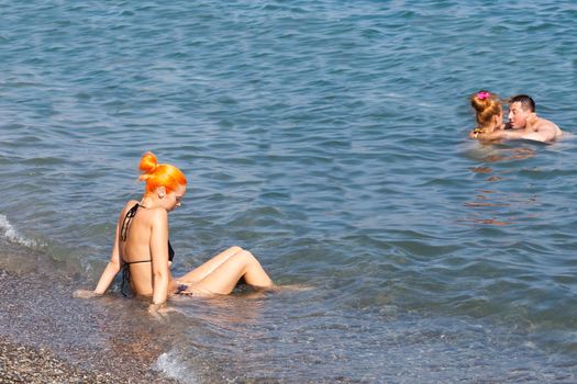 ALUSHTA,RUSSIA-September 06:beautiful the girl sits on the seashore,RUSSIA-SEPTEMBER 06 2015.In the Crimea many people sunbathe on the bank of the Black Sea