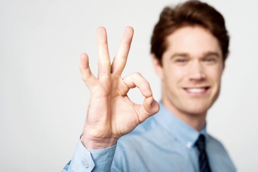 Happy young executive gesturing OK sign