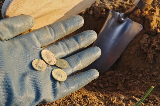 Treasure retrieved while metal detecting. Metal detector coil, spade and gloves. Sports and hobbies theme