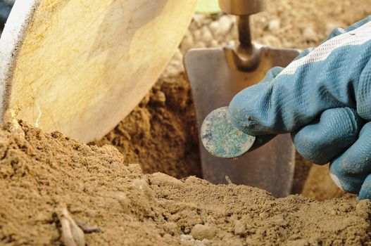 Retrieving treasure while metal detecting. Metal detector coil, spade and gloves. Sports and hobbies theme