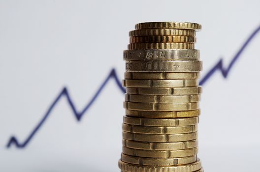 A pile stack of coins (Euros and British Pounds) and a rising financial chart line behind