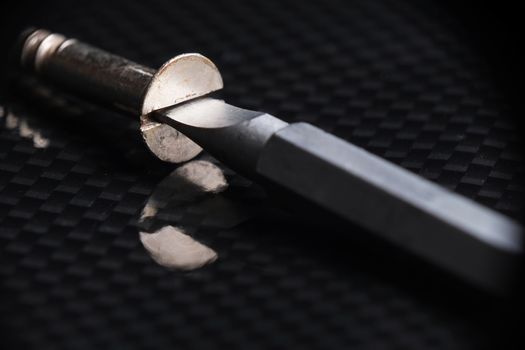 Bolt and screwdriver on top of a reflective carbon fiber surface