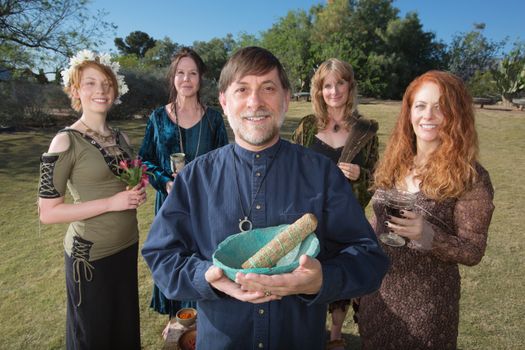 Modern Wicca priest holding sage smudge stick outdoors