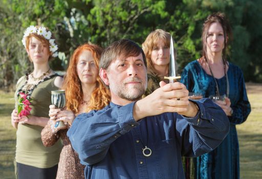 Bearded pagan priest with group and holding ritual knife