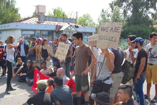 SERBIA, Horgo�: Migrants gather holding signs and flags in Horgo�, Serbia on September 17, 2015. Recently the migrants have clashed with police forcing the police to use tear gas and water cannons to hold the refugees at bay. The migrants demanded that the razor-wire fence be opened, which would allow them to continue their journey though Europe. 