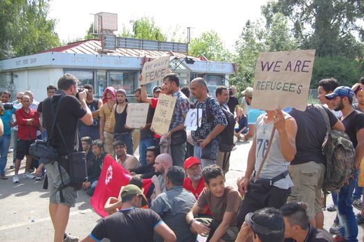 SERBIA, Horgo�: Migrants gather holding signs and flags in Horgo�, Serbia on September 17, 2015. Recently the migrants have clashed with police forcing the police to use tear gas and water cannons to hold the refugees at bay. The migrants demanded that the razor-wire fence be opened, which would allow them to continue their journey though Europe. 