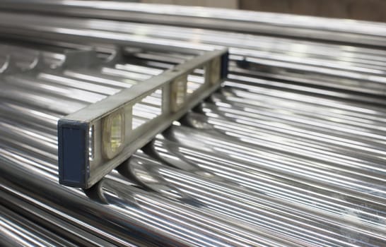 Level on a stack of steel tubes. Very shallow depth of field with only the nearest tubes and end of the level in focus.