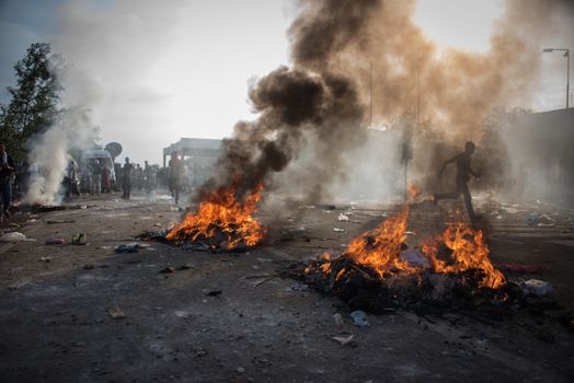 SERBIA, Horgos: Items burn as Hungarian riot police clash with refugees waiting to cross the border from the Serbian border town of Horgos on September 16, 2015. 