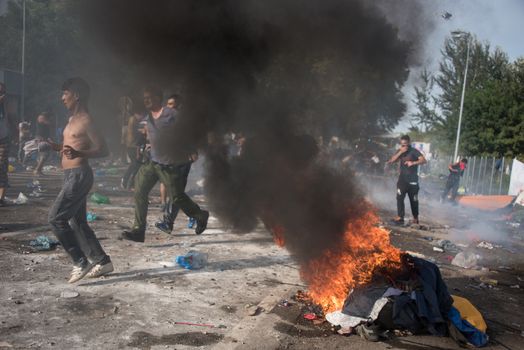 SERBIA, Horgos: Items are set on fire as Hungarian riot police clash with refugees waiting to cross the border from the Serbian border town of Horgos on September 16, 2015. 