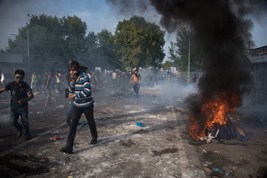 SERBIA, Horgos: Items are set on fire as Hungarian riot police clash with refugees waiting to cross the border from the Serbian border town of Horgos on September 16, 2015. 