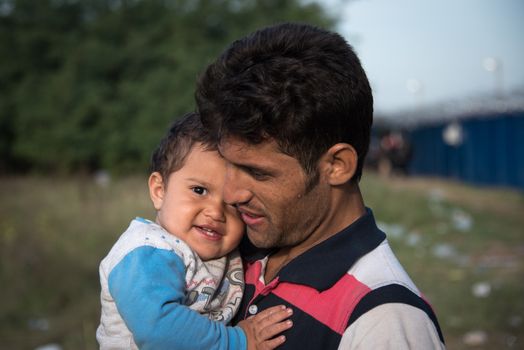 SERBIA, Horgos: A refugee carries his child as he waits to cross the border in the Serbian border town of Horgos on September 15, 2015.  