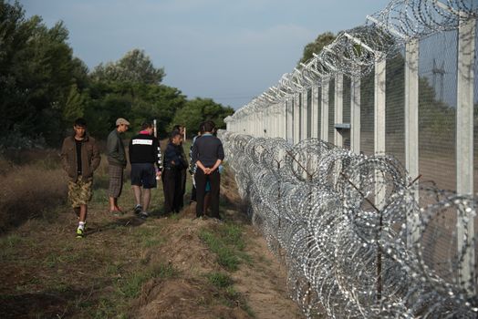 SERBIA, Horgos: Refugees walk along the fence marking the border between Serbia and Hungary in the Serbian border town of Horgos on September 15, 2015.  