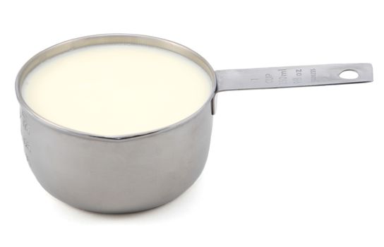 Milk in an American measuring cup, isolated on a white background