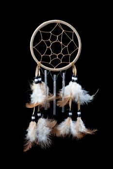 A small dream catcher with feathers, beads and chimes on a pure black background