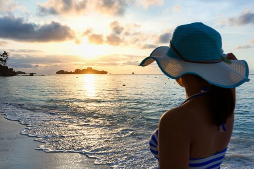 Girl with blue and white striped swimsuit standing watch nature sky and sea during the sunrise on beach of Honeymoon Bay at Koh Miang, Similan Islands National Park, Phang Nga, Thailand