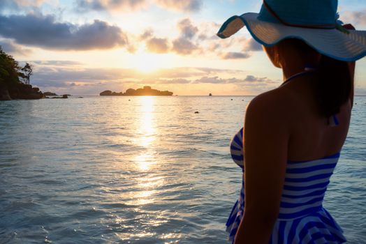 Girl with blue and white striped swimsuit standing watch nature sky and sea during the sunrise on beach of Honeymoon Bay at Koh Miang, Similan Islands National Park, Phang Nga, Thailand