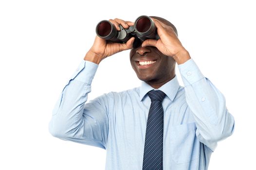 Smiling male executive peers through binocular