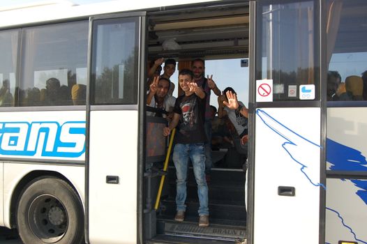 SERBIA, Border with Croatia: Refugees aboard a bus wave as hundreds are  stranded at the Serbian-Croatian border on September 18, 2015 after Croatia decided to shut their border with Serbia.This decision was made after more than 11,000 refugees entered Croatia in a single day. Refugees had to spend entire night and half of the next day at the border. Local authorities in Serbia have organized bus transportation to take the refugees from the border to the reception camps.