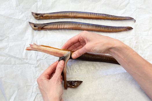 Female hands stripping  skin preparing eel fish