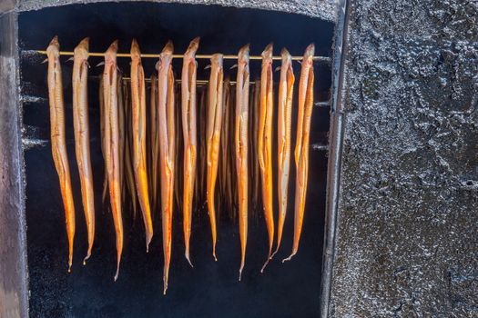 Many hanging brown eels are being smoked at market