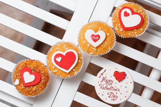 valentine's day muffins with red and white hearts on a white wooden table with a note