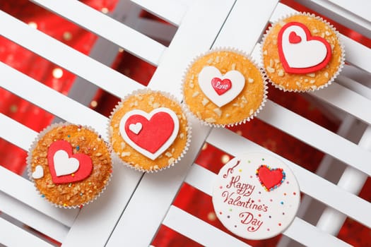 valentine's day muffins with red and white hearts on a white wooden table with a note