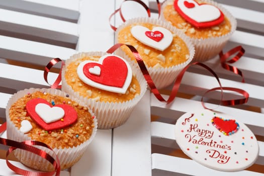 valentine's day muffins with red and white hearts on a white wooden table with a note and ribbon