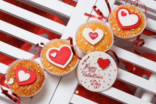 valentine's day muffins with red and white hearts on a white wooden table with a note and ribbon