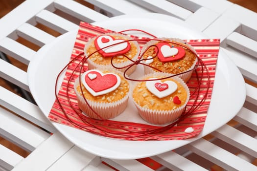 white plate with valentine's day muffins with red and white hearts on a white wooden table