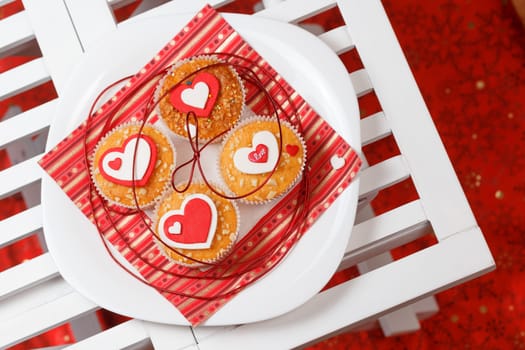 white plate with valentine's day muffins with red and white hearts on a white wooden table