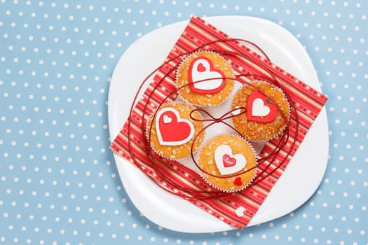 white plate with valentine's day muffins with red and white hearts on a blue in white dots background (polka dot)