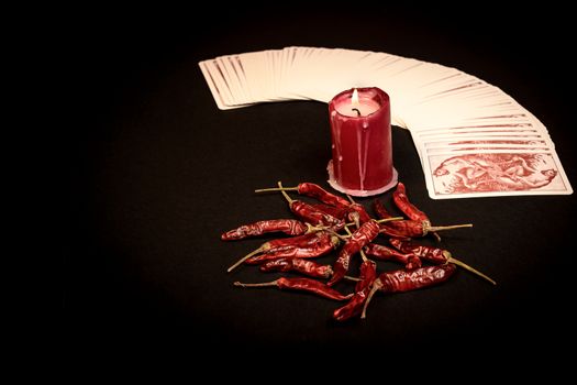 In the pictured a deck of cards open fan , a red candle and red pepper dry.