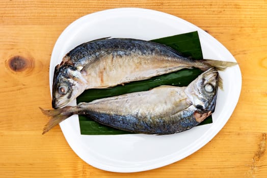 steam with mackerel in white dish on wood table