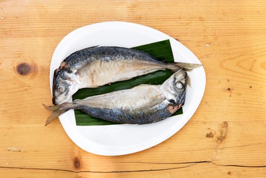 steam with mackerel in white dish on wood table .