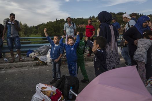 CROATIA, Harmica: Young refugee children chant and hold their arms in the air on a bridge in the village of Harmica, Croatia on the border of Slovenia on September 19, 2015, after the Slovenian government blocked refugees from entering the country with riot police. Slovenia is the latest country to be forced into action over the global refugee crisis, with Slovenia's ambassador to Germany telling the Rheinische Post newspaper they will accept 'up to 10, 000' refugees