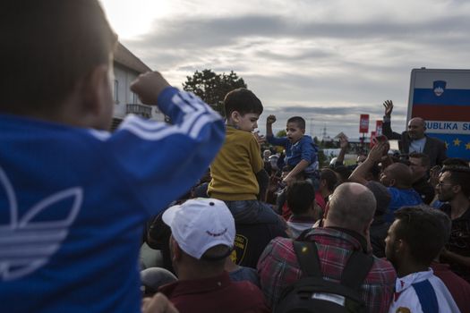 CROATIA, Harmica: Young refugee children sit on their parent's shoulders while a crowd forms in the village of Harmica, Croatia on the border of Slovenia on September 19, 2015, after the Slovenian government blocked refugees from entering the country with riot police. Slovenia is the latest country to be forced into action over the global refugee crisis, with Slovenia's ambassador to Germany telling the Rheinische Post newspaper they will accept 'up to 10, 000' refugees