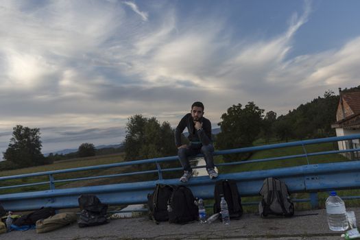 CROATIA, Harmica: A refugees sits and waits on a bridge railing in the village of Harmica, Croatia on the border of Slovenia on September 19, 2015, after the Slovenian government blocked refugees from entering the country with riot police. Slovenia is the latest country to be forced into action over the global refugee crisis, with Slovenia's ambassador to Germany telling the Rheinische Post newspaper they will accept 'up to 10, 000' refugees