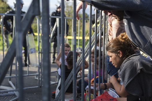 CROATIA, Harmica: Refugees sit and wait near a barricade while Slovenian riot police watch them from the other side in Harmica, Croatia on the border of Slovenia on September 19, 2015. The Slovenian government blocked refugees from entering the country after thousands of refugees descended on the border