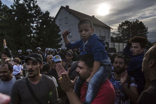 CROATIA, Harmica: A young refugee child sits on their parent's shoulders while a crowd forms in the village of Harmica, Croatia on the border of Slovenia on September 19, 2015, after the Slovenian government blocked refugees from entering the country with riot police. Slovenia is the latest country to be forced into action over the global refugee crisis, with Slovenia's ambassador to Germany telling the Rheinische Post newspaper they will accept 'up to 10, 000' refugees