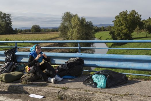 CROATIA, Harmica: A refugee sits and waits on a bridge with her belongings in the village of Harmica, Croatia on the border of Slovenia on September 19, 2015, after the Slovenian government blocked refugees from entering the country with riot police. Slovenia is the latest country to be forced into action over the global refugee crisis, with Slovenia's ambassador to Germany telling the Rheinische Post newspaper they will accept 'up to 10, 000' refugees